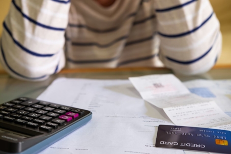 Close up shot of people who check financial invoice and income statement and use calculator to calculate for personal or credit card expense.